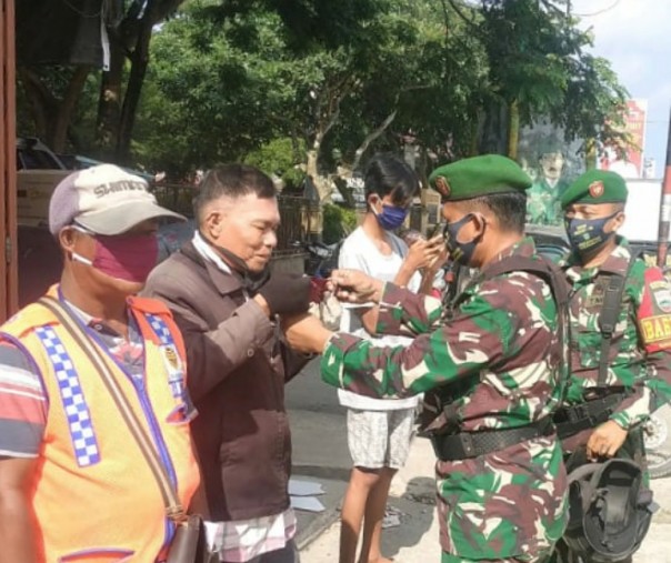 Danramil 08 Tandun Kapten (Arm) Alza Septendi bersama anggota patroli saat memberikan masker pada pengunjung Pasar Ujungbatu, Jumat (26/6/2020). Foto: Istimewa.