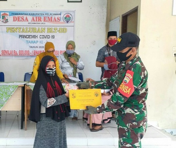 Babinsa Air Emas Serka Samsul Wahidin saat menyerahkan BLT DD secara simbolis kepada warga, Sabtu (27/6/2020). Foto: Istimewa.