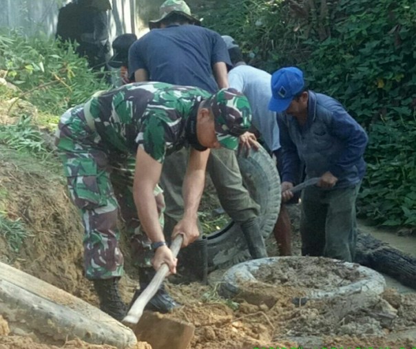 Babinsa Desa Beringin Makmur Sertu Hermansyah saat membantu warga membuat parit, Sabtu (4/7/2020). Foto: Istimewa.