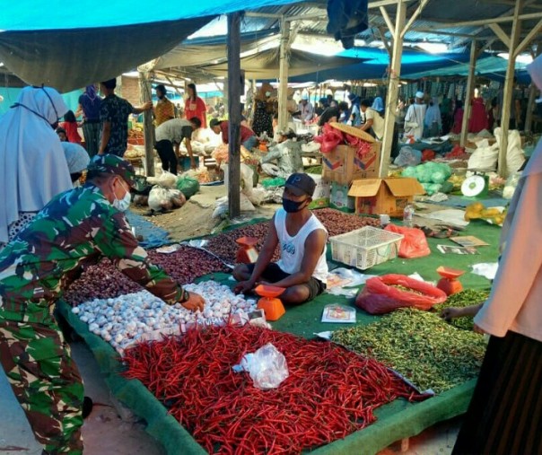 Babinsa Koramil 15 Kuala Kampar Sertu Hermansyah saat bercengkrama dengan salah seorang pedagang di Pasar Tradisional Desa Bukit Lembah Subur, Kecamatan Kerumutan, Kabupaten Pelalawan, Minggu (5/7/2020). Foto: Istimewa.