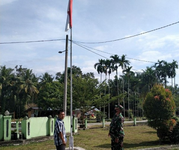 Babinsa Koramil 01 Bangkinang saat mengecek kondisi bendara Merah Putih yang dipasang di perkantoran, Rabu (8/7/2020). Foto: Istimewa.