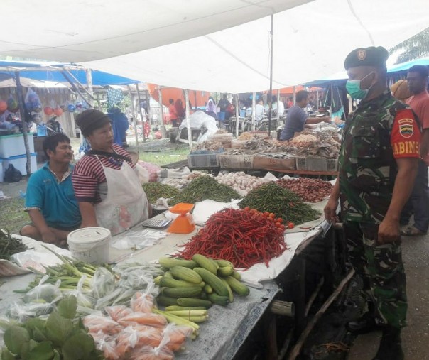 Babinsa Koramil 05 Kampar Kiri Serka Nusirwan memantau harga bahan pokok di pasar tradisional Desa Sungai Lipai, Kecamatan Gunung Sahilan, Kabupaten Kampar, Jumat (10/7/2020). Foto: Istimewa.