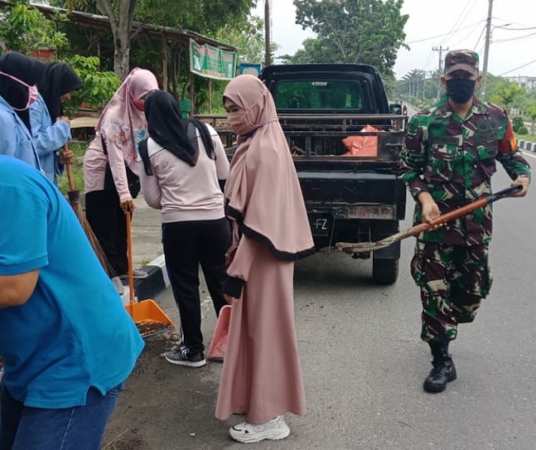 Babinsa Koramil 06 Siak Hulu Pelda Budiman bersama mahasiswa KKN membersihkan jalan raya di Perumahan Pandau Permai, Jumat (10/7/2020). Foto: Istimewa.