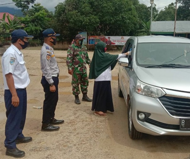 Babinsa Koramil 13 Rokan Kopda Febrianto bersama di tim Satgas Gugus Tugas Percepatan Penanganan Covid-19 Rohul memeriksa suhu tubuh pengendara di Kecamatan Rokan IV Koto, Sabtu (11/7/2020). Foto: Istimewa.