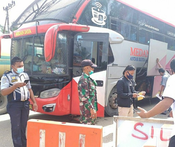 Babinsa Puo Raya Serma Harman bersama tim gabungan saat memeriksa suhu tubuh penumpang bus yang akan berangkat ke Sumatera Utara melalui Kabupaten Rohul, Riau, Minggu (12/7/2020). Foto: Istimewa.