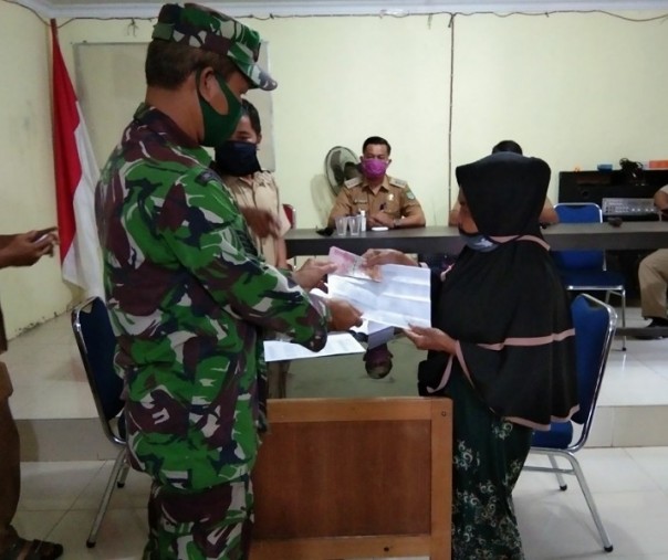 Babinsa Koramil 13 Rokan Pendalian Serma Muhar menyerahkan secara simbolis BLT DD tahap ketiga kepada masyarakat yang kurang mampu di Desa Pendalian, Rohul, Selasa (14/7/2020). Foto: Istimewa.