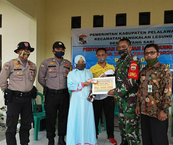 Babinsa Koramil 04 Pangkalan Kuras Pelda Alek Hermawan menyalurkan BLT DD secata simbolis di Kantor Desa Mayang Sari, Pelalawan, Jumat (24/7/2020). Foto: Istimewa.