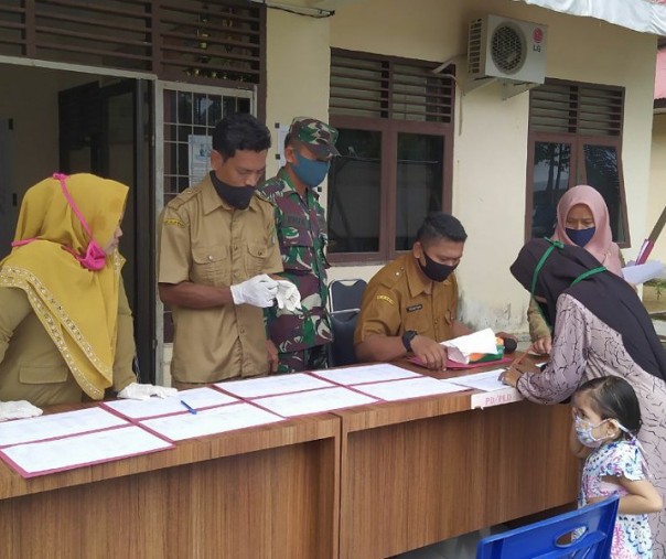 Babinsa Koramil 13 Rokan Serma Ifrijal mengawasi penyaluran BLT DD tahap ketiga di kantor Desa Alahan, Rohul, Selasa (28/7/2020). Foto: Istimewa.