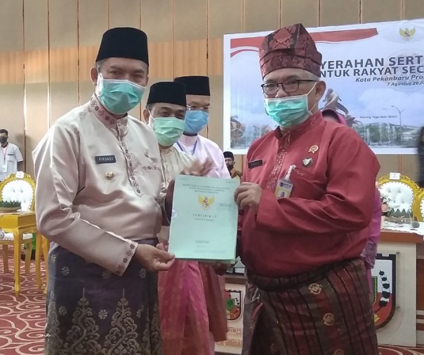 Wali Kota Pekanbaru Firdaus saat menerima sertifikat tanah Kompleks Perkantoran Tenayan Raya dari BPN Pekanbaru Ronald, Jumat (7/8/2020). Foto: Surya/Riau1.