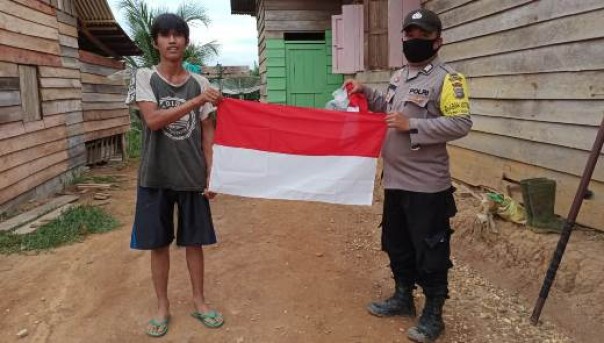 Personel Bhabinkamtibmas Polsek Kelayang membagikan bendera merah putih gratis kepada suku talang mamak, Jumat 8 Agustus 2020
