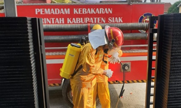 Petugas pemadam melakukan sterilisasi di rumah pasien AD di Kecamatan Tualang Siak