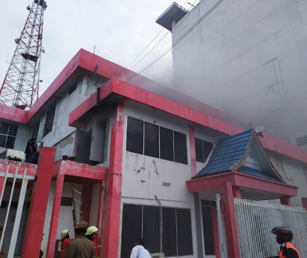 Api membakar salah satu gedung di area plasa Telkom Jalan Jenderal Sudirman Pekanbaru. Bangunan ini berada di belakang. Tampak petugas memadamkan api.