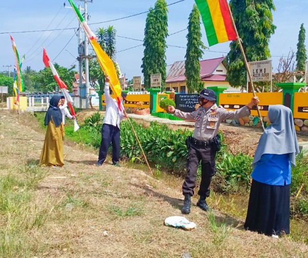 Kanit Binmas Polsek Pangkalan Lesung Ipda Yandri mengajak pegawai Kantor Desa Mulya Subur memasang umbul-umbul dan bendera Merah Putih, Selasa (12/8/2020). Foto: Istimewa.