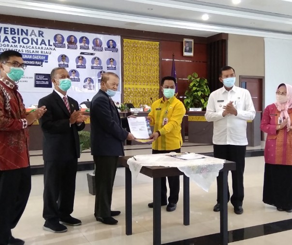 Penjabat Sekdako Pekanbaru M Jamil bersama Direktur Pascasarjana UIR Profesor Yusri Munaf melihatkan dokumen perjanjian kerja sama yang telah diteken disaksikan Wali Kota Firdaus dan Rektor UIR, Kamis (13/8/2020). Foto: Surya/Riau1.