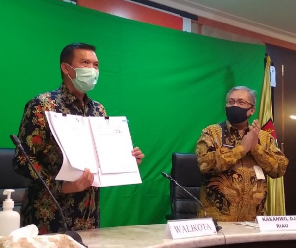 Wali Kota Pekanbaru Firdaus saat melihatkan dokumen kerja sama yang ditandatangani dengan Kepala Kanwil DPJ Riau Farid Bachtiar, Rabu (26/8/2020). Foto: Surya/Riau1.