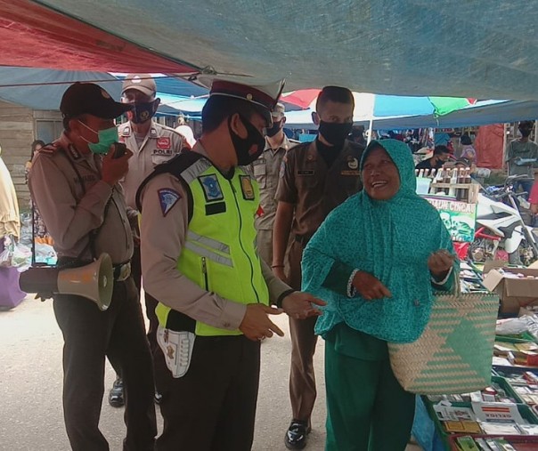 Personel Polsek Pangkalan Kuras menegur warga yang tak mengenakan masker saat berbelanja di pasar, Minggu (20/9/2020). Foto: Istimewa.