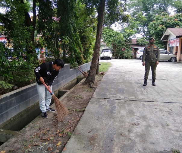 Seorang warga yang tak mengenakan masker dihukum menyapu halaman Kantor Kelurahan Simpang Baru di Jalan Soebrantas, Kecamatan Tampan, Senin (21/9/2020). Foto: Surya/Riau1.