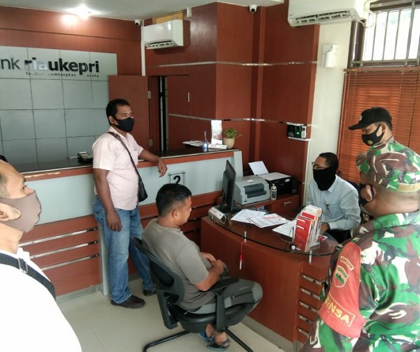 Personel Polsek Teluk Meranti, TNI, dan Satpol PP menegur seorang warga yang tak mengenakan masker di Kantor Bank Riau Kepri, Senin (21/9/2020). Foto: Istimewa.