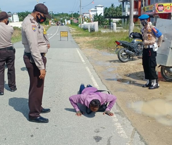 Seorang warga pengendara yang tak mengenakan masker dihukum push up oleh personel Polsek Bunut, Kamis (24/9/2020). Foto: Istimewa.