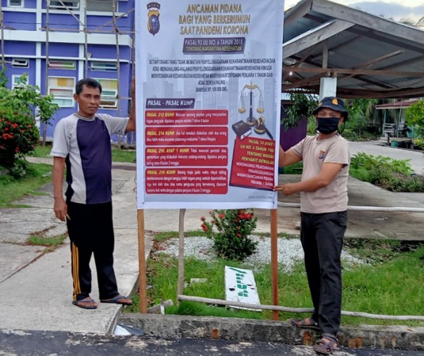 Personel Polsek Kuala Kampar menyebar spanduk soal hukuman pidana bagi warga yang tak mematuhi protokol kesehatan di masa pandemi corona, Rabu (23/9/2020) petang. Foto: Istimewa.