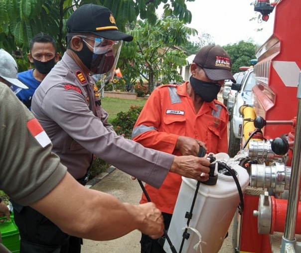 Kapolsek Ukui AKP Rifendi ikuti mengisi tangki penyemprot dengan cairan disinfektan, Kamis (1/10/2020). Foto: Istimewa.