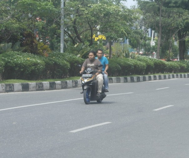 Pengendara dan penumpang motor tak mengenakan masker dan helm di Jalan Arifin Ahmad, Pekanbaru, Senin (19/10/2020). Foto: Istimewa.
