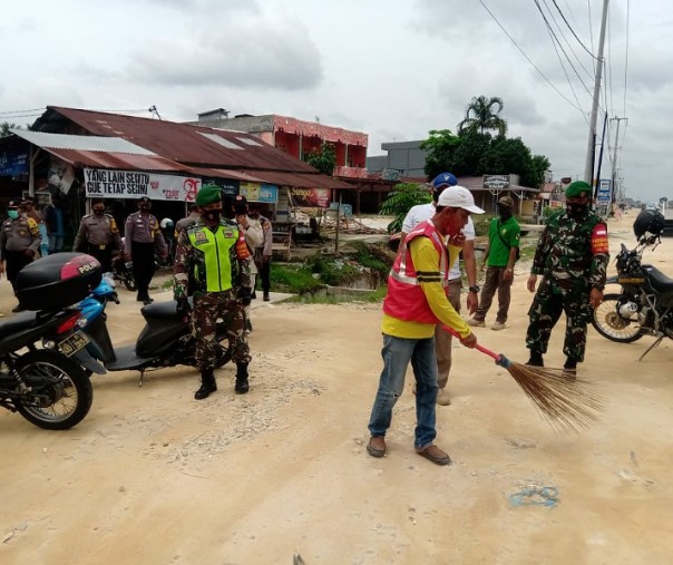 Seorang warga terjaring razia masker mengenakan rompi merah sedang menyapu jalan, Jumat (23/10/2020). Foto: Satpol PP Pekanbaru.