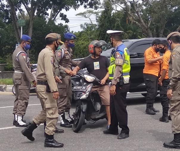 Seorang pengendara motor terjaring razia masker di gerbang kawasan Purna MTQ Pekanbaru, Jalan Jenderal Sudirman, Senin (26/10/2020). Foto: Surya/Riau1.