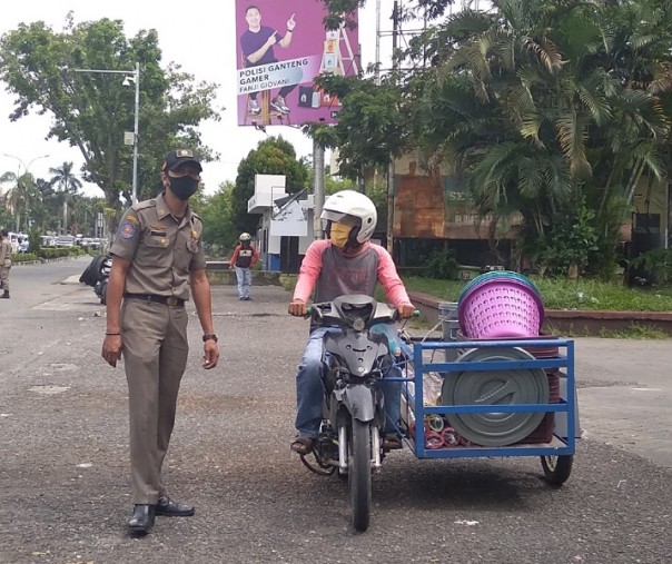 Petugas Satpol PP Pekanbaru menegur pengendara becak motor agar memasang masker di gerbang Purna MTQ, Senin (26/10/2020). Foto: Surya/Riau1.