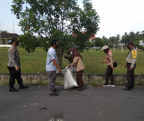 Personel Polsek Kuala Kampar, anggota Pramuka, dan aparatur kecamatan membersihkan area di sekitar lapangan sepak bola di Kelurahan Teluk Dalam, Rabu (28/10/2020). Foto: Istimewa.