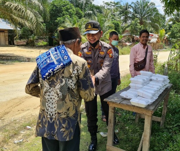 Kapolsek Langgam Ipda M Fadlillah membagikan nasi kotak kepada jemaah Masjid Raya Al Falah di Dusun II, Desa Tambak, Kecamatan Langgam, Jumat (30/10/2020). Foto: Istimewa.