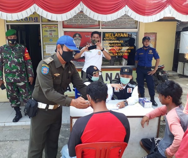 Petugas Satpol PP Pekanbaru memasangkan masker ke warga yang terjaring razia, Jumat (30/10/2020). Foto: Satpol PP Pekanbaru.