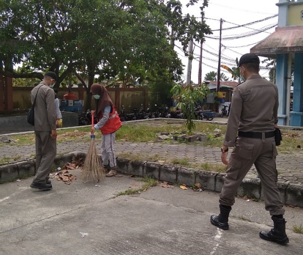 Petugas Satpol PP Pekanbaru mengarahkan warga yang terjaring razia masker saat menyapu area parkir Pasar Rumbai, Senin (2/11/2020). Foto: Surya/Riau1.
