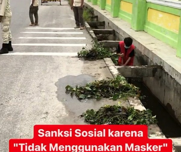 Seorang warga yang terjaring razia masker sedang menjalani hukuman membersihkan parit di Jalan Jendral, Labuhbaru Timur, Payung Sekaki, Rabu (4/11/2020). Foto: Instagram Satpol PP Pekanbaru.