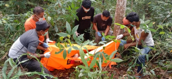 Petugas dibantu warga sekitar mengevakuasi mayat korban dari dalam kebun karet