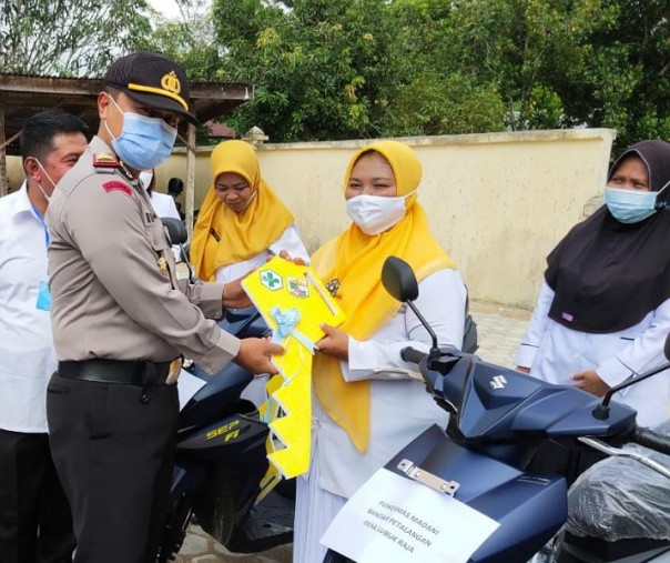 Kapolsek Bunut AKP Rokhani menyerahkan secara simbolis kunci motor kepada bidan di Bandar Petalangan, Rabu (18/11/2020). Foto: Istimewa.