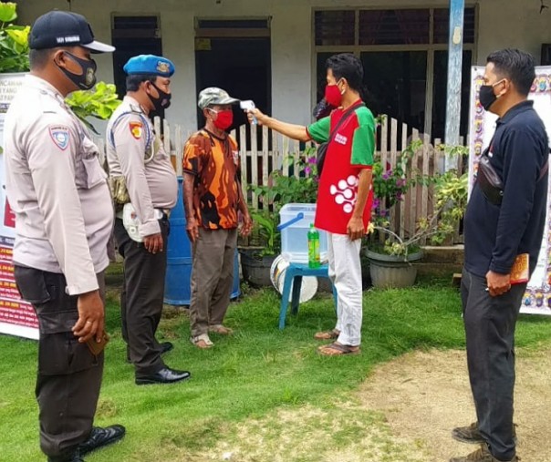 Salah seorang pendukung cakada Pelalawan menjalani pemeriksaan suhu tubuh sebelum memasuki lokasi kampanye, Selasa (24/11/2020). Foto: Istimewa.