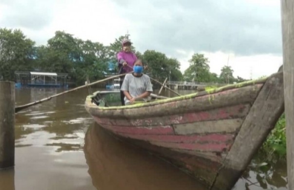 Ibu Awo menarik ojek sampan di Sungai Siak