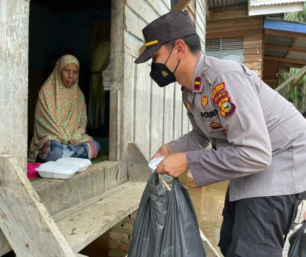 Kapolsek Langgam Ipda M Fadlillah mengantarkan nasi kota ke rumah warga yang terdampak banjir, Jumat (27/11/2020). Foto: Istimewa.