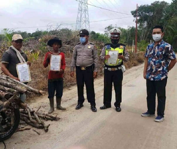 Personel Polsek Pangkalan Kuras membagikan selebaran Maklumat Kapolda Riau ke warga, Jumat (27/11/2020). Foto: Istimewa.