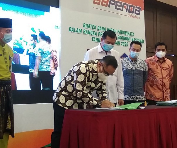 Pimpinan Hotel Aryaduta meneken berkas penerimaan dana hibah pusat disaksikan Wali Kota Pekanbaru Firdaus dan pihak Kementerian Dalam Negeri, Jumat (27/11/2020). Foto: Surya/Riau1.