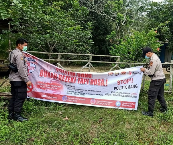 Personel Polsek Bunut saat memasang spanduk cegah politik uang di Kecamatan Bunut dan Kecamatan Bandar Petalangan, Kabupaten Pelalawan, Minggu (29/11/2020). Foto: Istimewa.