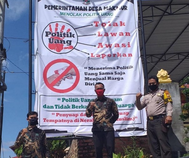 Personel Polsek Pangkalan Kerinci usai memang spanduk tolak politik uang, Sabtu (5/12/2020). Foto: Istimewa. 