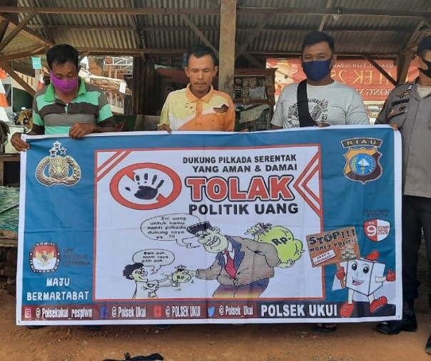 Personel Polsek Ukui saat sosialisasi anti politik uang, Minggu (6/12/2020). Foto: Istimewa.
