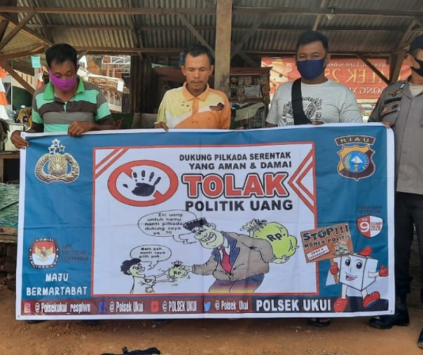 Personel Polsek Ukui saat sosialisasi anti politik uang, Minggu (6/12/2020). Foto: Istimewa. 