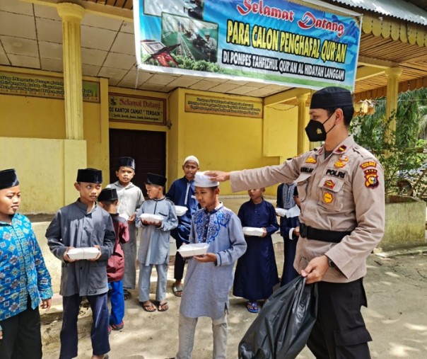 Kapolsek Langgam Ipda M Fadlillah membagikan nasi kotak kepada para santri yang berada di Ponpes Tahfizul Quran, Jumat (11/12/2020). Foto: Istimewa.
