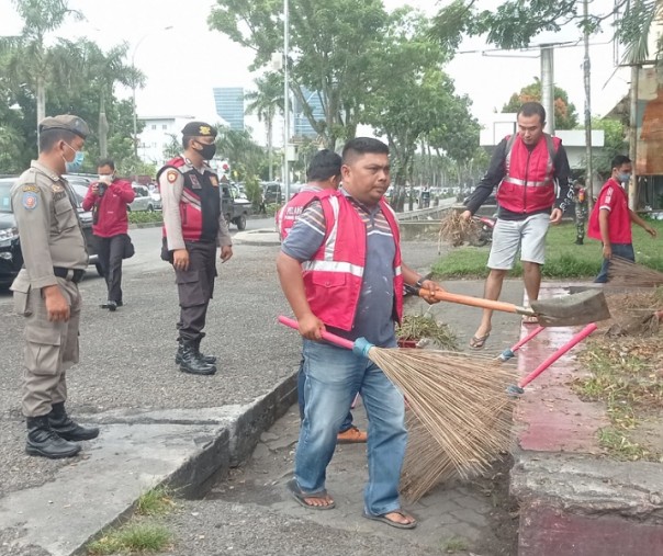 Yogi saat ikut bersama warga yang tak mengenakan masker membersihkan kawasan Purna MTQ Pekanbaru, Kamis (7/1/2021). Foto: Surya/Riau1.