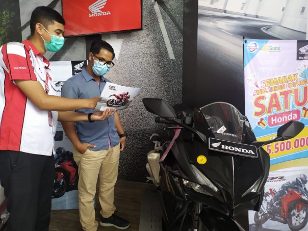 Marketing Capella Honda Riau memperlihatkan brosur kepada konsumen yang berkunjung ke showroom