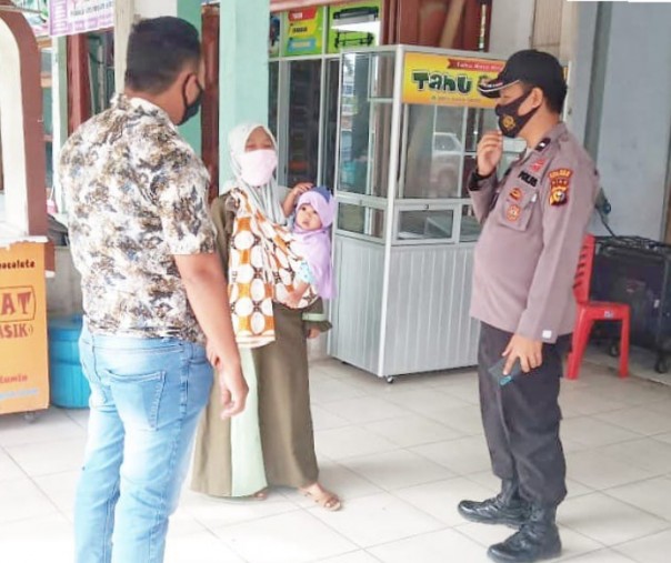 Personel Polsek Pangkalan Kerinci saat mensosialisasikan penggunaan masker kepada seorang warga, Sabtu (16/1/2021). Foto: Istimewa.
