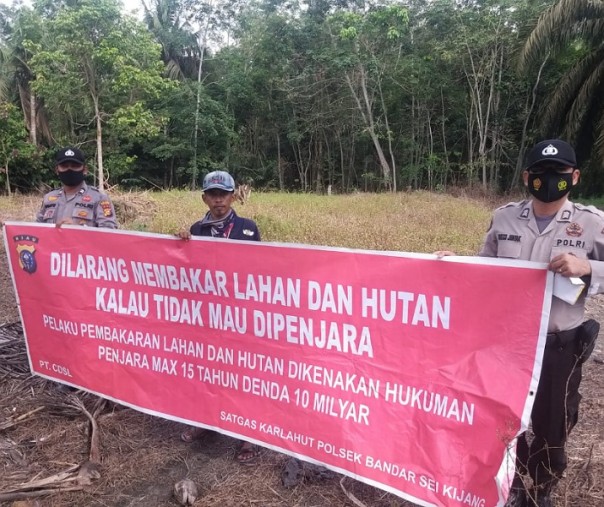 Personel Polsek Bandar Sei Kijang memasang spanduk larangan membakar hutan dan lahan di Desa Kiyab Jaya, Minggu (17/1/2021). Foto: Istimewa. 